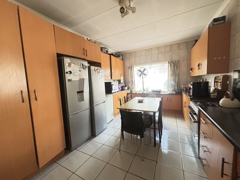 A functional kitchen featuring extensive built-in cabinetry, tiled flooring, and wall tiling, equipped with a gas hob and oven.