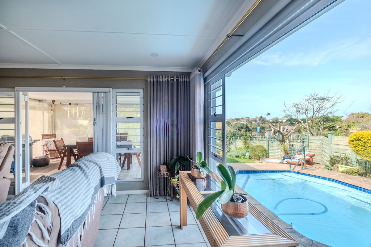 Bright living area featuring large sliding glass doors that open onto a patio and swimming pool, offering seamless indoor-outdoor flow.
