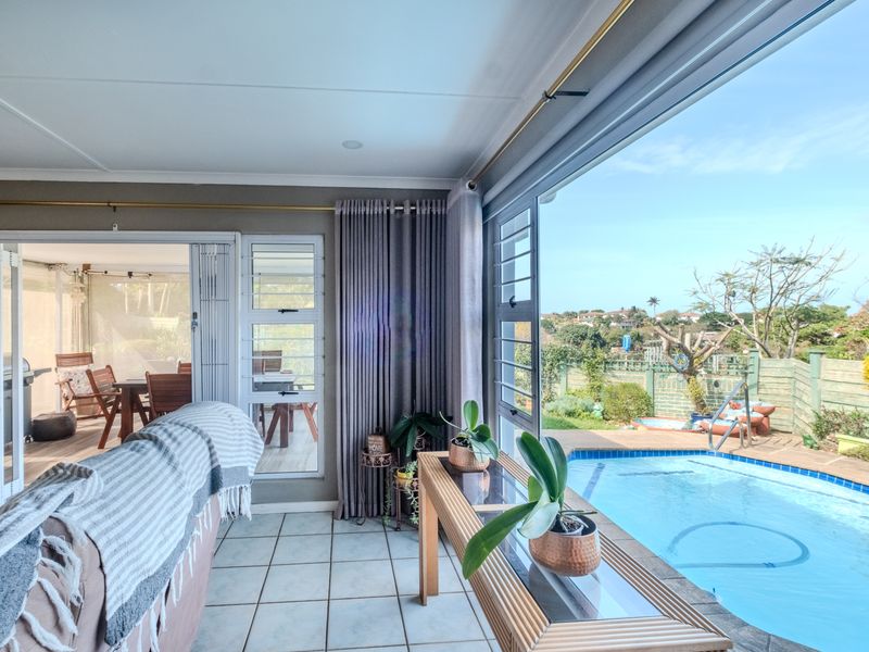 Bright living area featuring large sliding glass doors that open onto a patio and swimming pool, offering seamless indoor-outdoor flow.