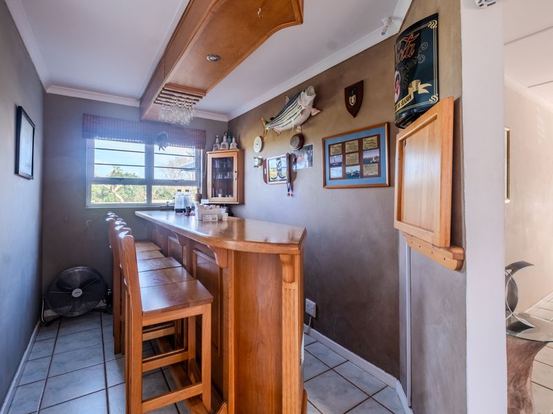 A dedicated bar area featuring a built-in wooden counter, overhead canopy, and tiled flooring, offering a functional space for entertaining.