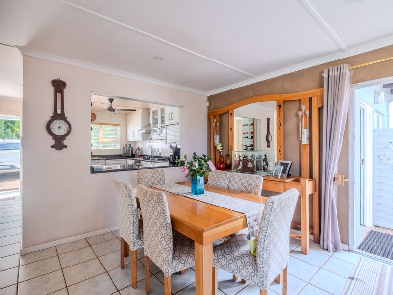 Open plan dining area featuring tiled flooring, a built-in wooden wall unit, and a convenient pass-through window connecting to the kitchen space.