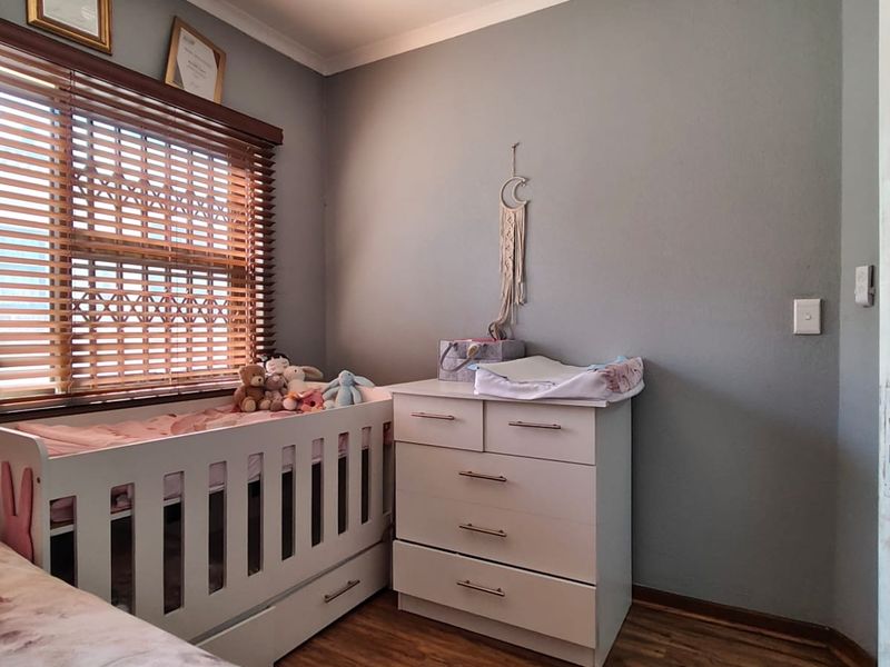 A cozy bedroom featuring laminate flooring, a ceiling fan, and wooden blinds, providing a comfortable and functional living space.