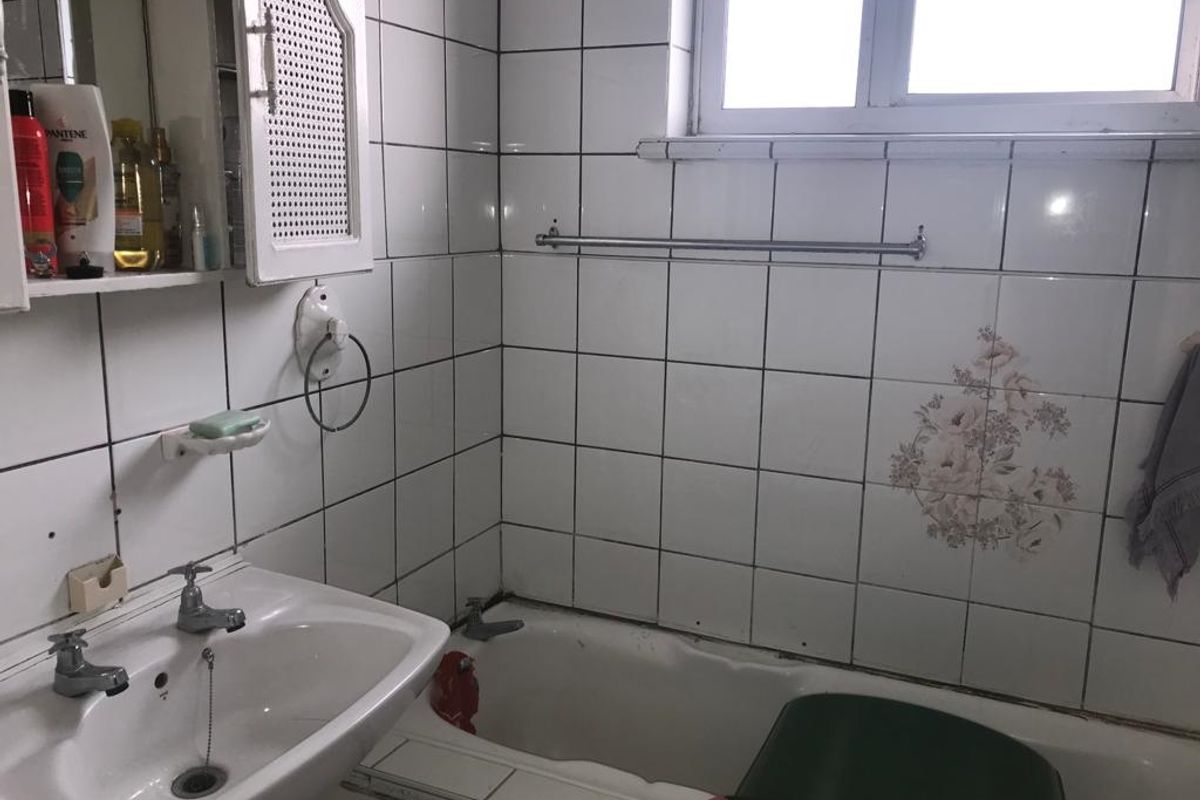 A dated bathroom featuring a pedestal basin, bathtub, and tiled walls. The space would benefit from modern updates to fixtures and finishes.