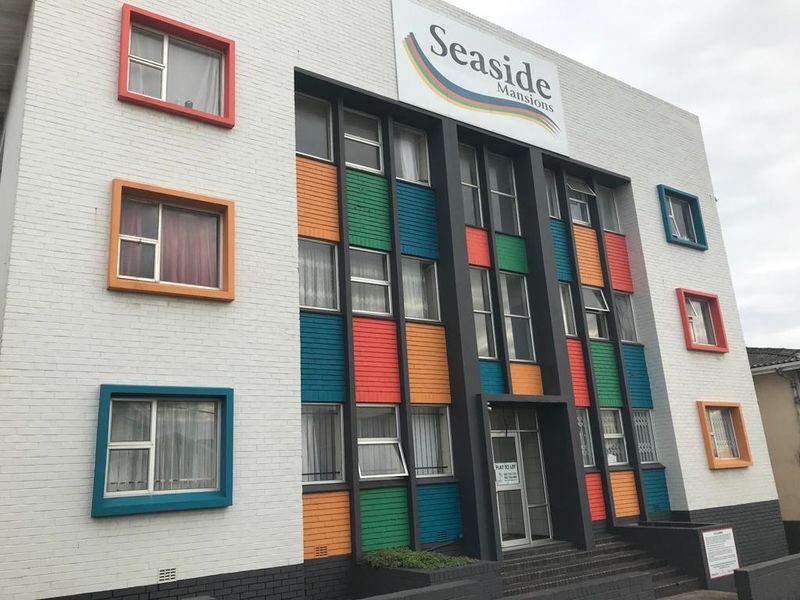 Front exterior view of Seaside Mansions, featuring a multi-colored painted brick facade and aluminium window frames.