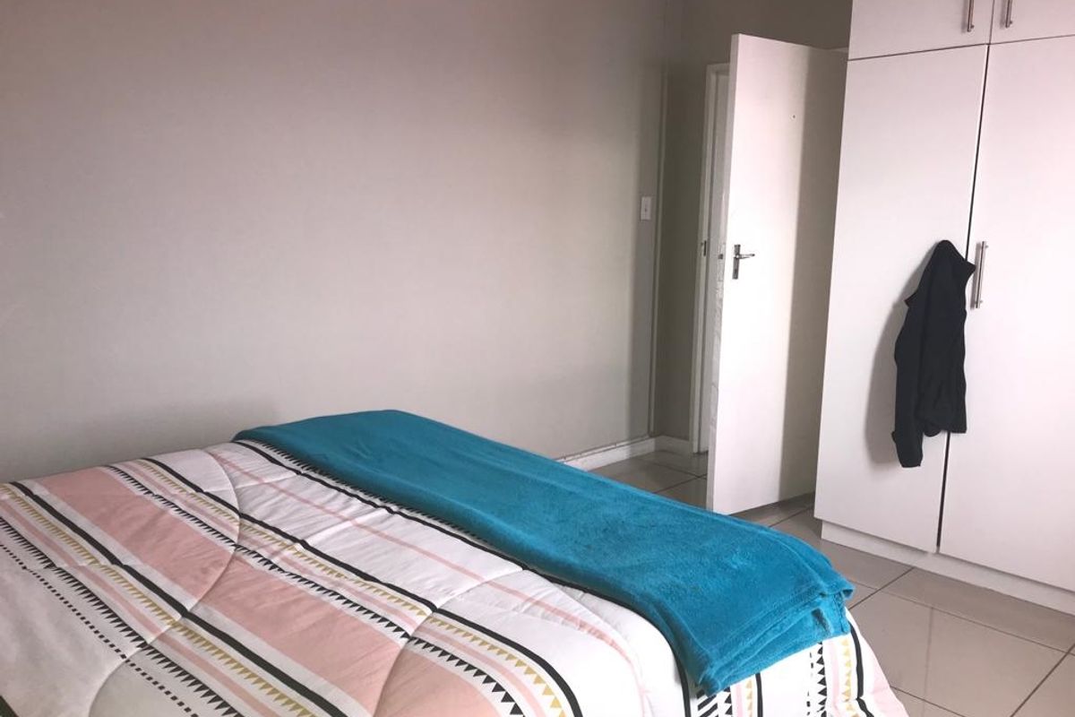 A bedroom featuring tiled flooring and a built-in wardrobe with white cabinetry.
