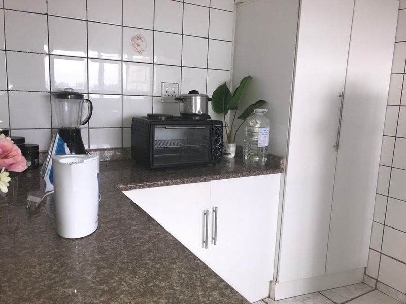 A functional kitchen area featuring granite countertops, white cabinetry, and a tiled backsplash, providing a practical workspace with integrated storage.