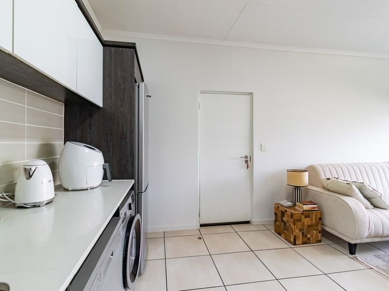 An open-plan living area featuring a modern kitchen with sleek cabinetry, stone countertops, and tiled flooring, seamlessly connecting to the adjacent living space.
