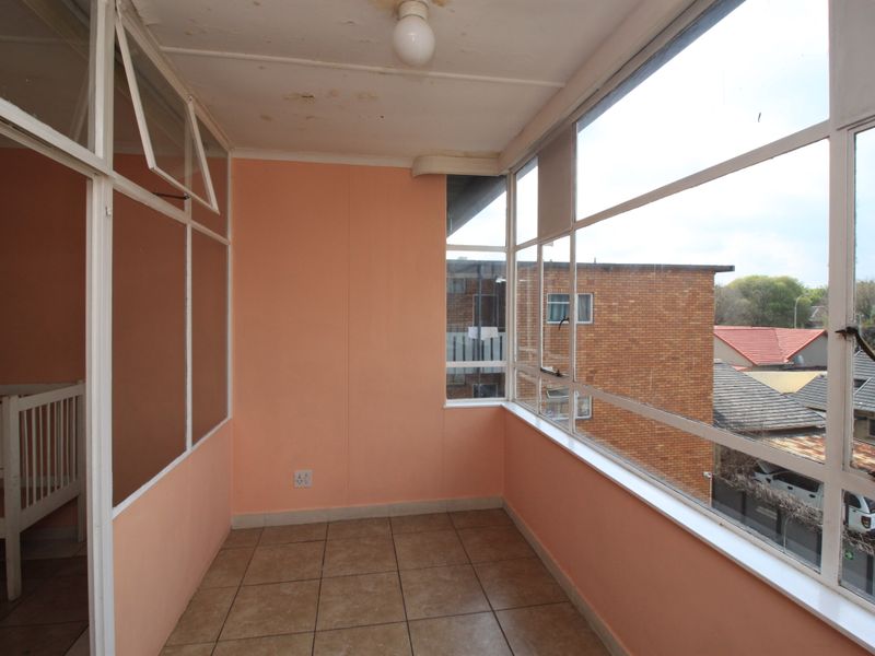 Enclosed balcony area featuring tiled flooring and large windows, offering natural light and views of the surrounding neighborhood.