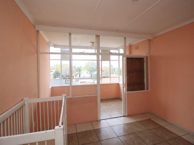 An enclosed balcony area featuring tiled flooring, a glass partition wall, and large windows providing natural light and exterior views.