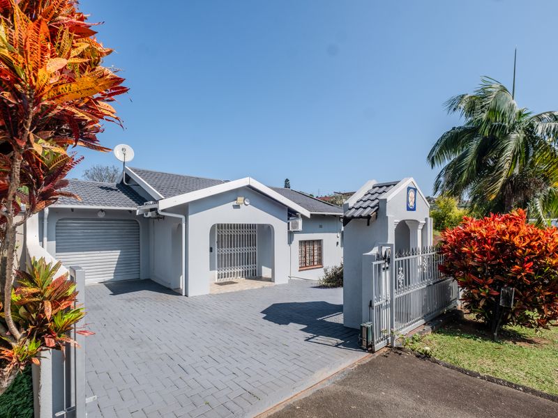 Front elevation of a well-maintained house featuring a paved driveway, single garage with roller door, and secure gated entrance.