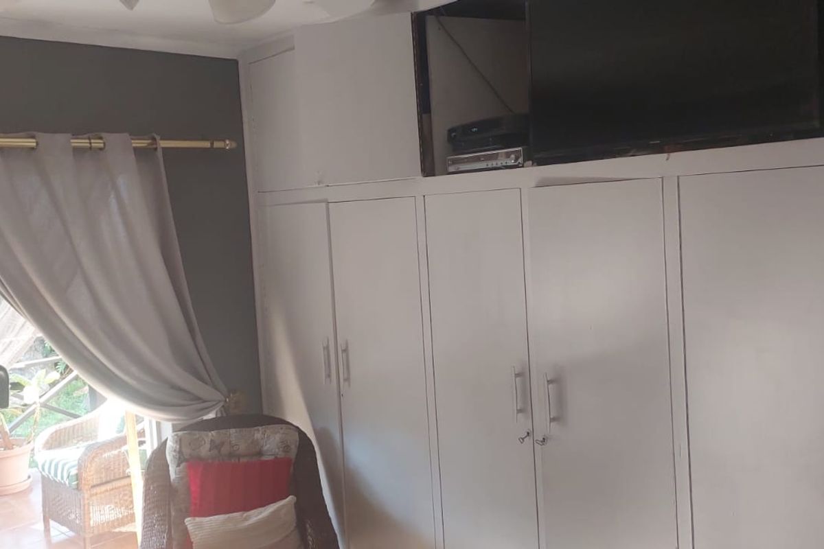 Bedroom featuring built-in cupboards with some visible damage to the cabinetry and a sliding door providing access to an outdoor area.
