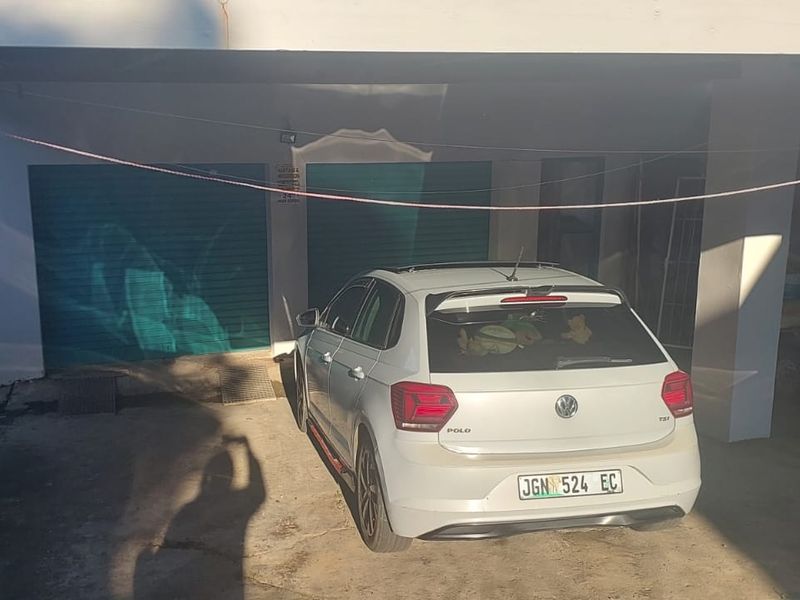 A covered double garage area with concrete flooring and two roller shutter doors.