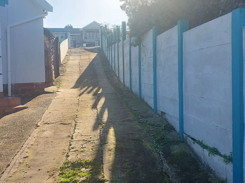 A view of the property's concrete driveway leading to the entrance, bordered by a precast concrete boundary wall.