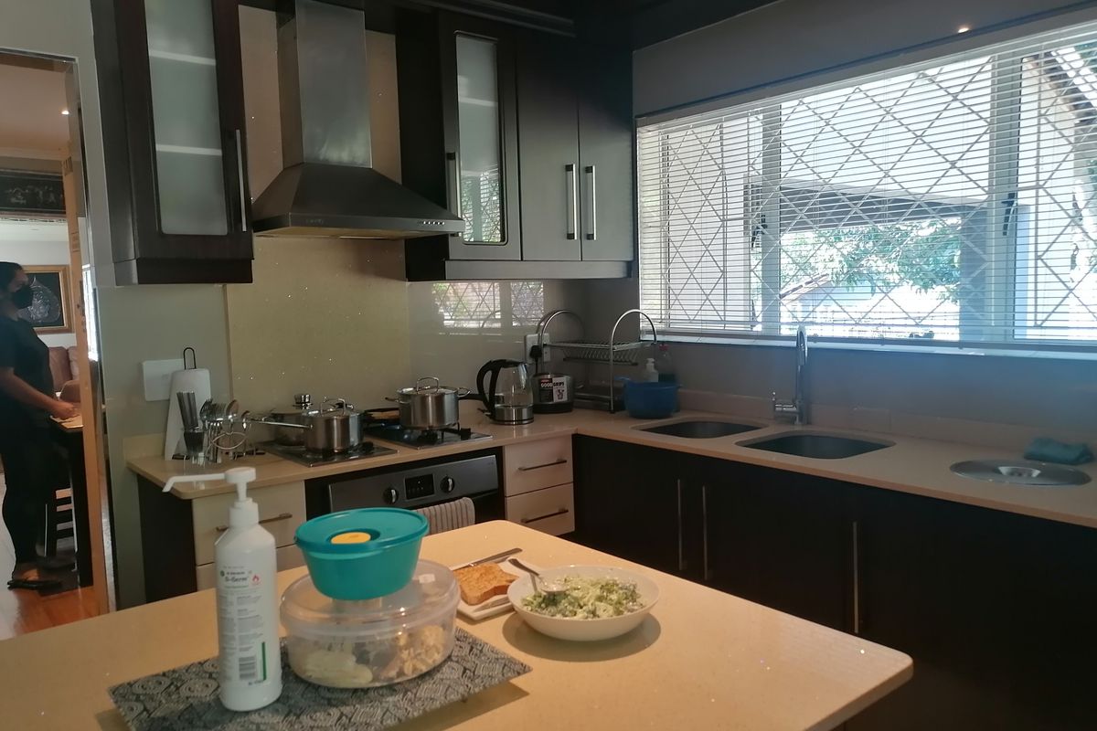 A functional kitchen featuring dark cabinetry, stone countertops, a gas hob with extractor fan, and a double sink with window views.