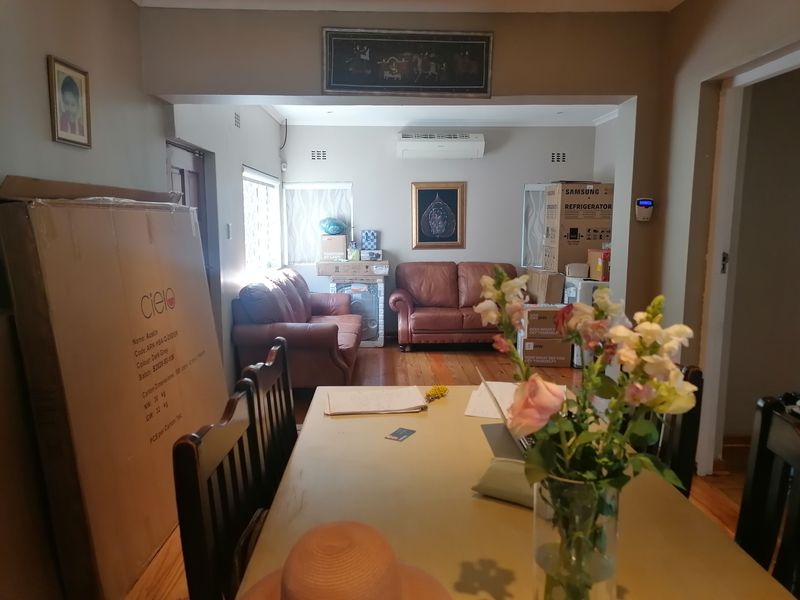 Open-plan living and dining area featuring polished hardwood flooring and a wall-mounted split-system air conditioner.