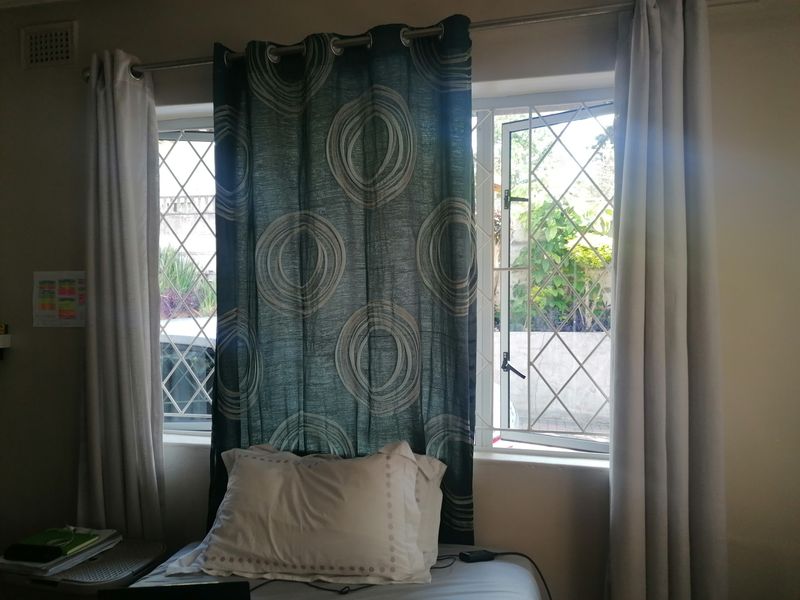 A bedroom featuring casement windows with integrated security bars, providing natural light and ventilation.