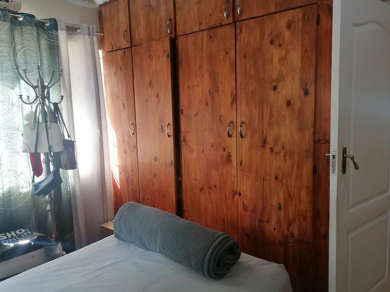 A bedroom featuring floor-to-ceiling built-in wooden cupboards providing ample storage space.