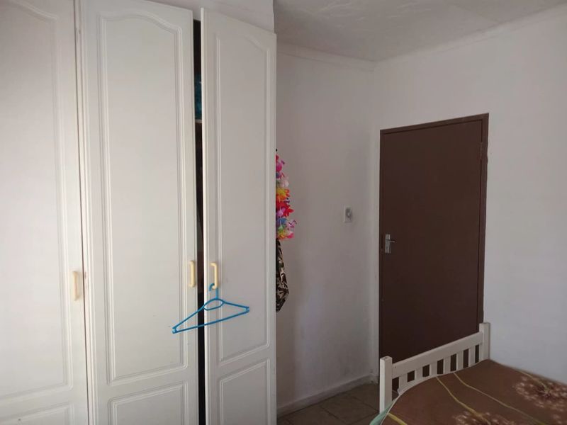 A bedroom featuring built-in white wardrobes and tiled flooring, requiring minor cosmetic updates to the wall finishes.