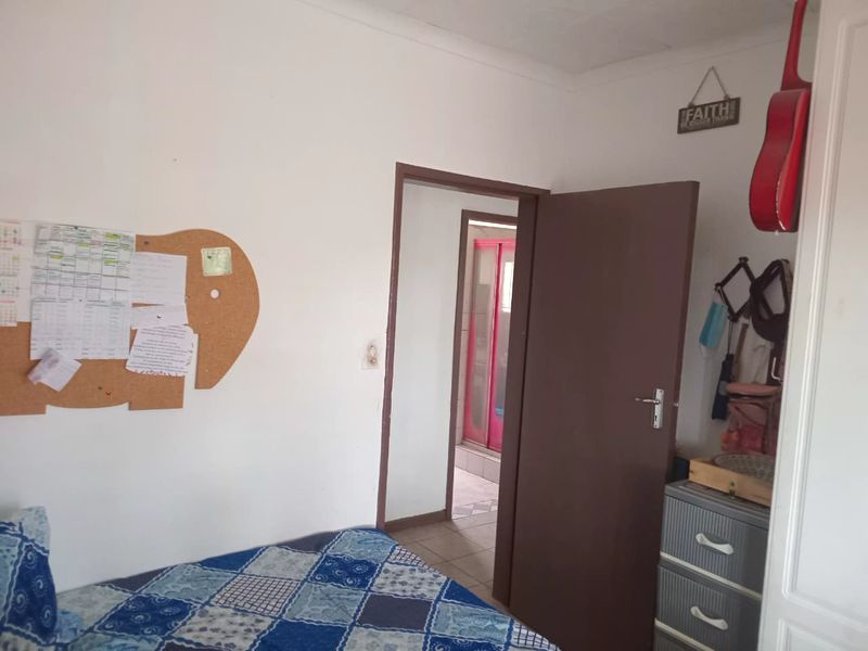 A bedroom interior featuring a doorway leading to an adjacent bathroom area with tiled flooring.