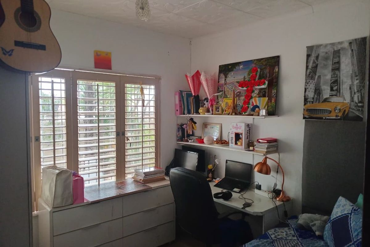 A bedroom featuring built-in shutters and wall-mounted shelving, providing a functional space with natural light.