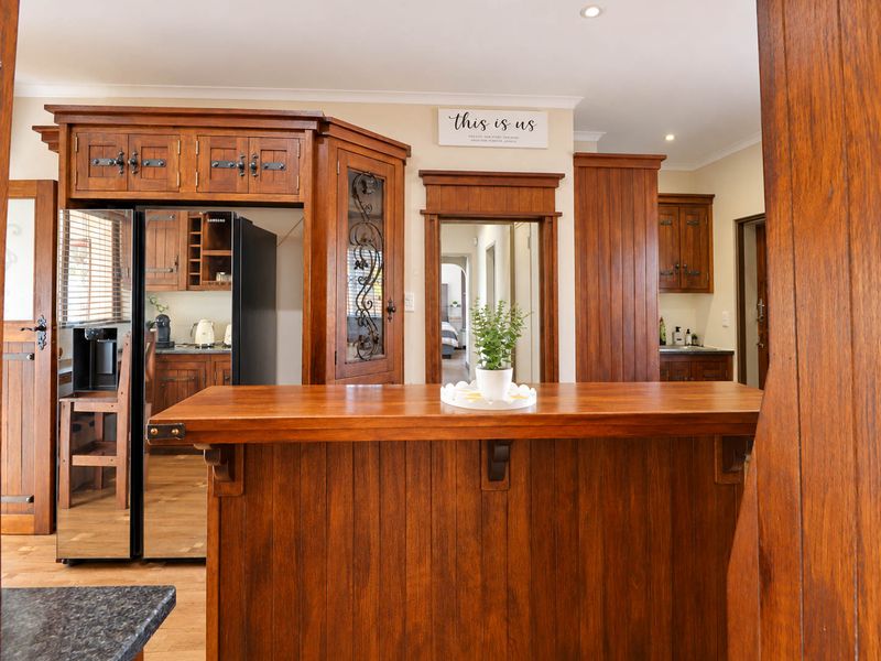 A traditional kitchen featuring extensive dark wood cabinetry, a central wooden island, and integrated storage solutions with a warm, classic aesthetic.