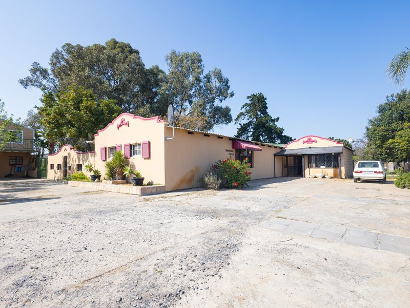 Front exterior view of a small holding property featuring a large concrete driveway, gabled roof architecture, and decorative window shutters.