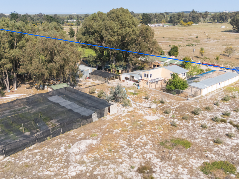 Aerial view of the small holding property featuring multiple outbuildings, shade netting structures, and solar panel installations set within a rural landscape.