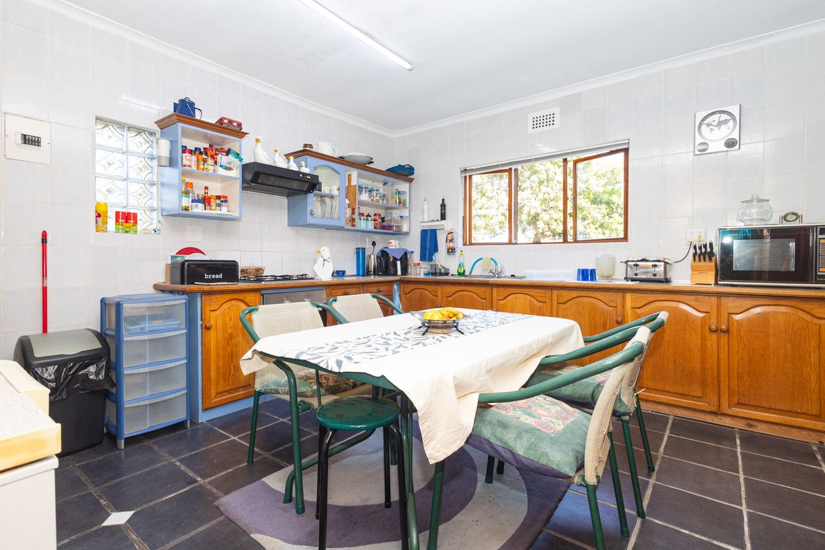 A functional kitchen featuring wooden cabinetry, tiled walls, and dark floor tiles, offering a classic layout with ample storage and prep space.