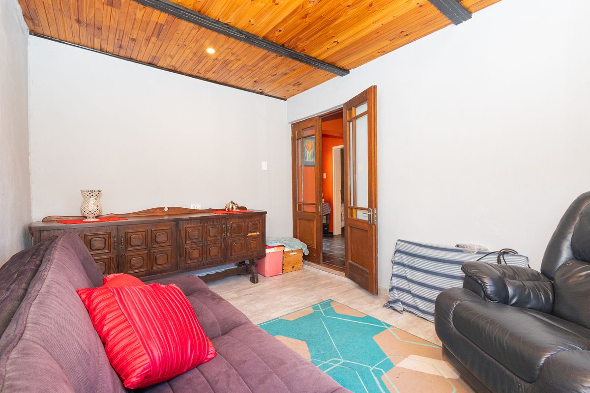 A living room featuring a warm timber-paneled ceiling and traditional wooden double doors leading to an adjacent space.