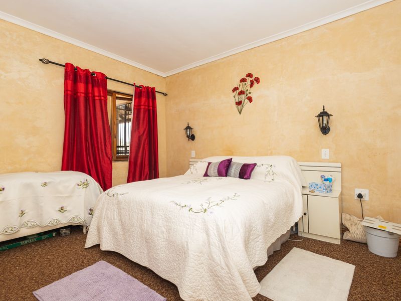 A bedroom featuring carpeted flooring, built-in bedside cabinetry, and wall-mounted lighting fixtures.