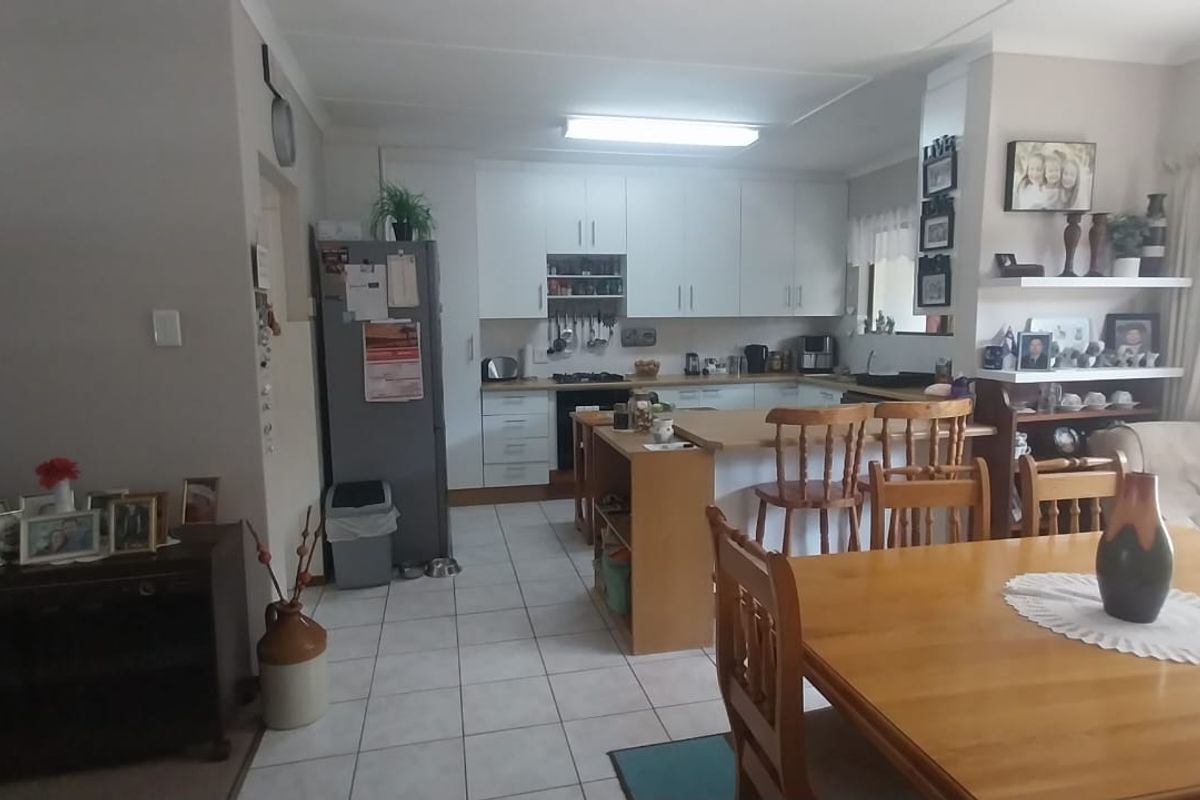 Open plan kitchen and dining area featuring tiled floors, white cabinetry, a central kitchen island, and sliding door access to the outdoor space.
