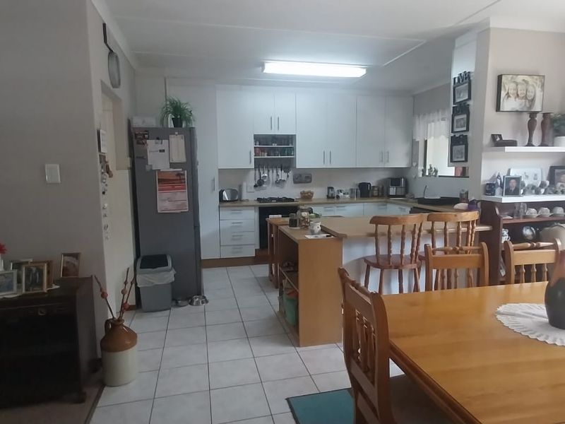 Open plan kitchen and dining area featuring tiled floors, white cabinetry, a central kitchen island, and sliding door access to the outdoor space.