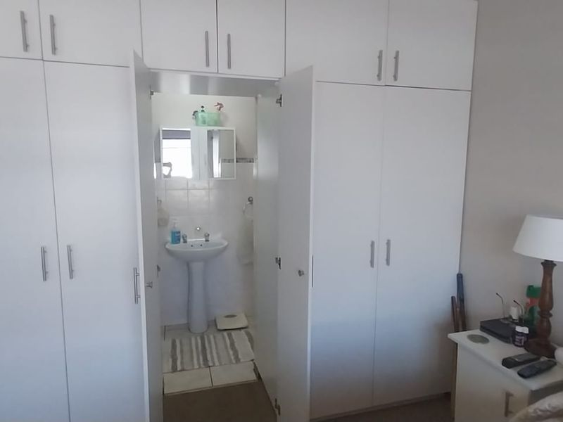 Bedroom featuring extensive built-in cupboard storage and an integrated en-suite basin area.
