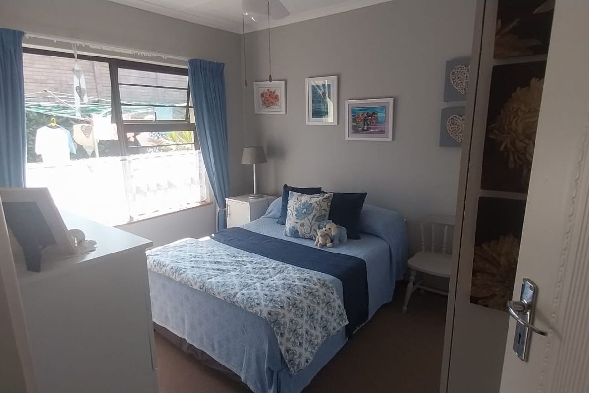 A cozy bedroom featuring a built-in wardrobe, neutral wall finishes, and a large window allowing natural light into the space.