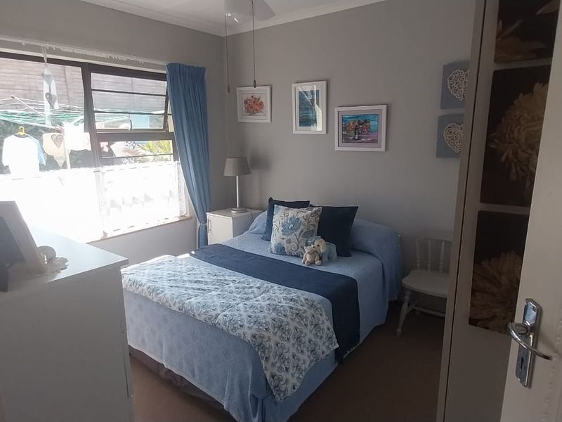 A cozy bedroom featuring a built-in wardrobe, neutral wall finishes, and a large window allowing natural light into the space.
