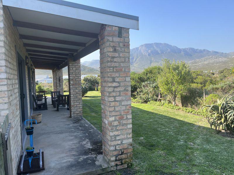 A covered patio featuring exposed brick columns and timber beams, offering direct access to the garden with scenic mountain views.