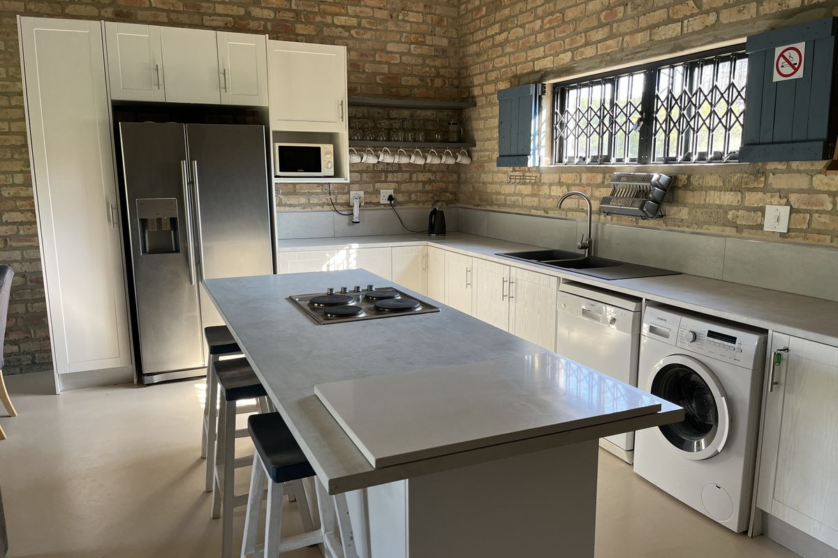 Modern kitchen featuring exposed brick walls, a central island with a built-in hob, integrated appliances, and ample cabinetry, offering a stylish industrial aesthetic.
