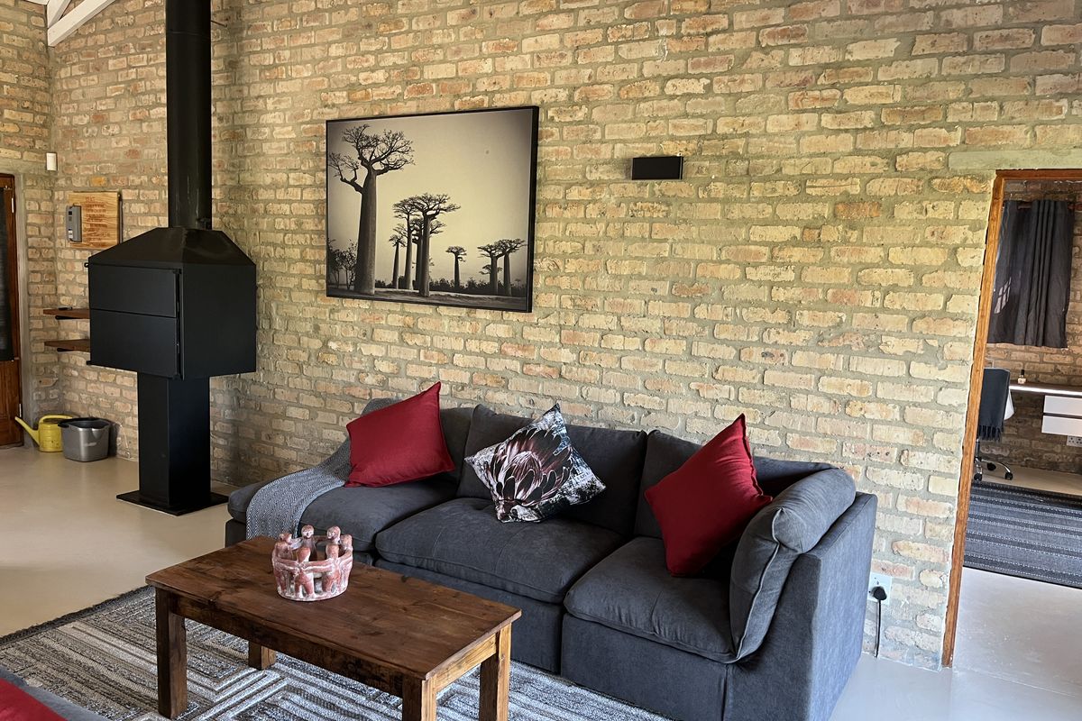 A cozy living room featuring a striking exposed brick wall, a modern freestanding fireplace, and a high vaulted ceiling.