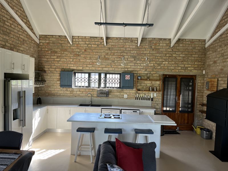 Spacious open-plan kitchen featuring exposed brick walls, vaulted ceilings, a central island with a built-in hob, and modern cabinetry.