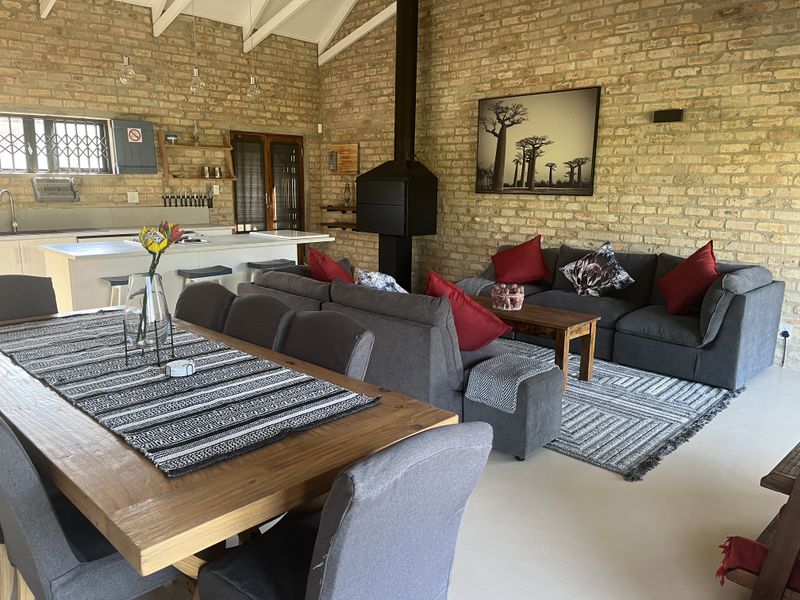 Spacious open-plan living area featuring exposed brick walls, a vaulted ceiling, a modern kitchen island, and a prominent freestanding fireplace.