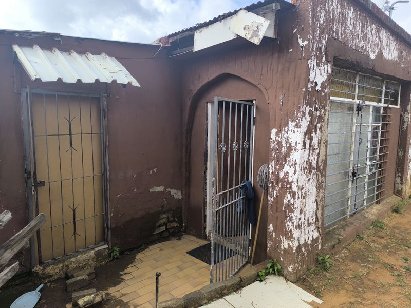 Front exterior view of the property showing significant wear to the facade, including peeling paint, damaged roof trim, and security gates.