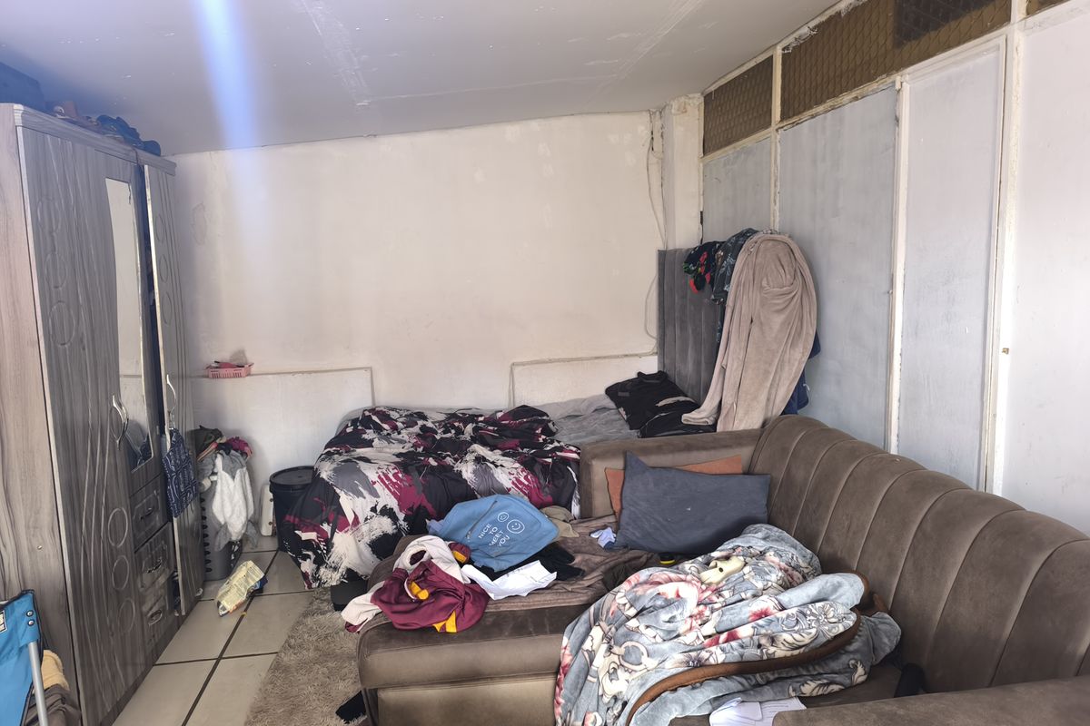 A bedroom featuring tiled flooring and a built-in wardrobe, currently showing signs of wear and requiring cosmetic updates to the walls and ceiling.