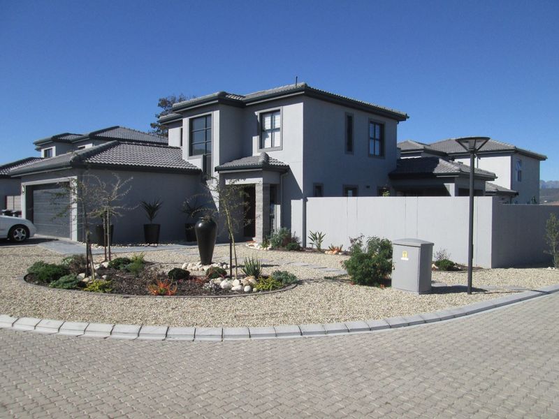 Modern double-storey residential home featuring a tiled roof, stone-clad accents, a double garage, and a neatly landscaped front garden with paved driveway.