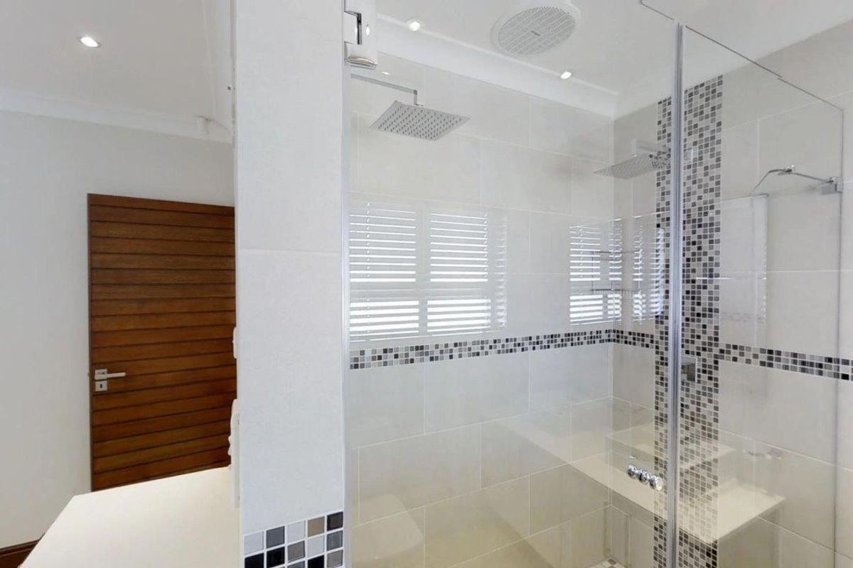 Modern bathroom featuring a spacious walk-in shower with a rain shower head, built-in bench, and stylish mosaic tile accents.