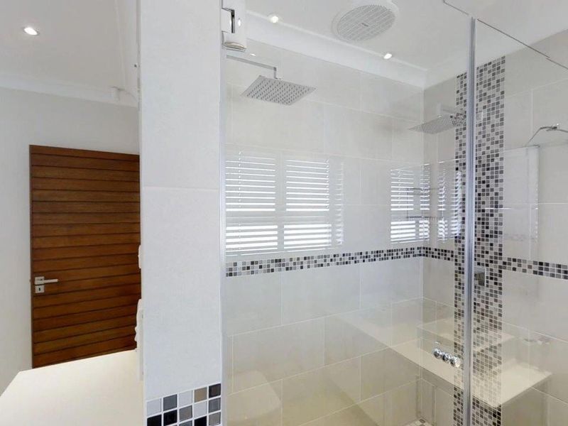 Modern bathroom featuring a spacious walk-in shower with a rain shower head, built-in bench, and stylish mosaic tile accents.