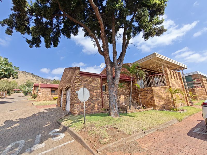 A well-maintained face brick townhouse featuring a covered patio, paved driveway, and integrated garage, situated in a quiet residential estate.