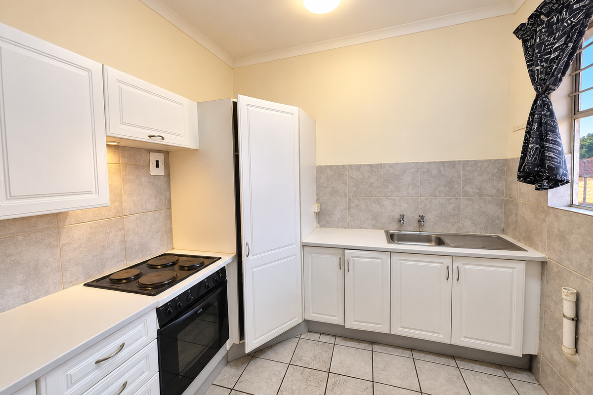 A functional kitchen featuring white cabinetry, a built-in electric oven and hob, tiled backsplash, and a stainless steel sink.