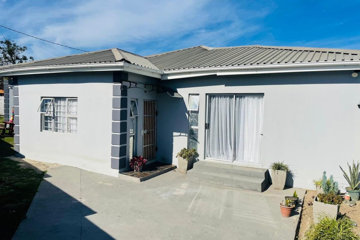 A well-maintained rear exterior view of the house featuring a concrete patio, sliding glass doors, and secure window fixtures.