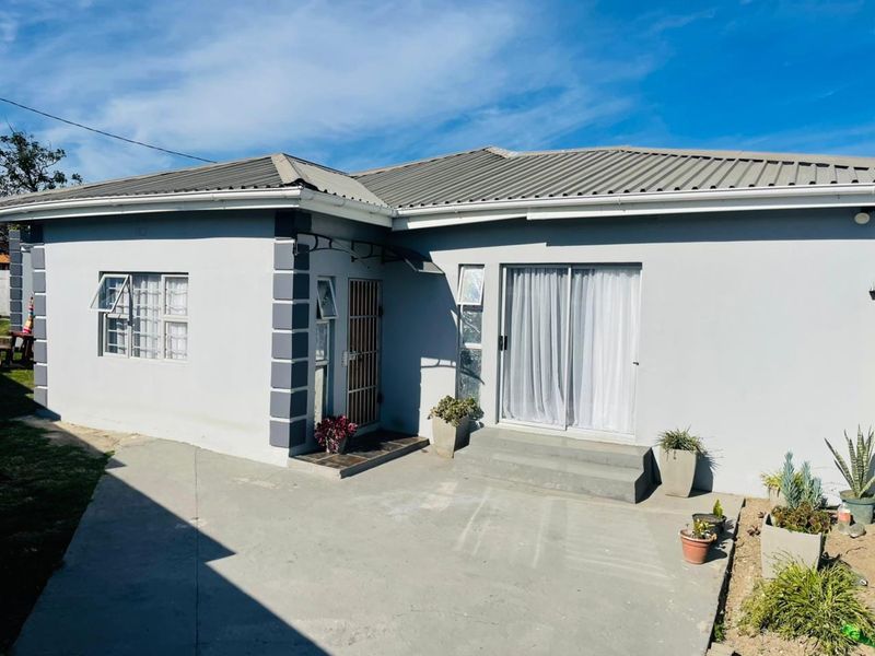 A well-maintained rear exterior view of the house featuring a concrete patio, sliding glass doors, and secure window fixtures.