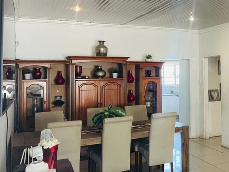 Dining room featuring tiled flooring and a corrugated metal ceiling, with an open transition to the adjacent kitchen area.